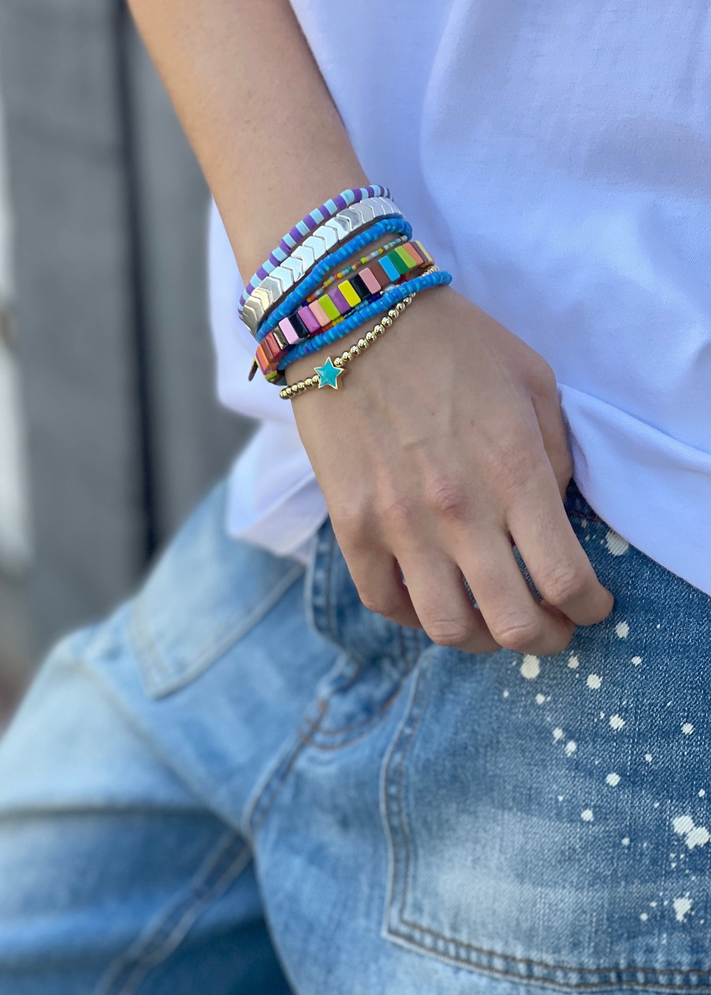 Hammill & Co Mixed blue  set of 8 bracelets on elastic. Features multicoloured beaded bracelet, multi cube enamel bracelets and gold bracelet with aqua star.