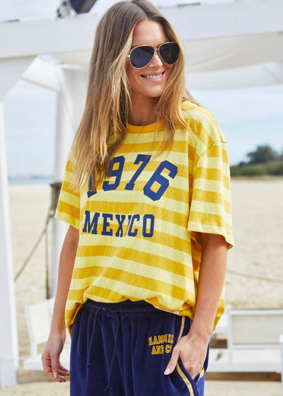 Hammill & Co Slouchy crew neck tee in a soft yellow and mustard stripe jersey with navy retro Mexico print on the front. Looks great worn back with the velour pants and shorts!