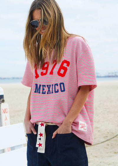 Hammill & Co tee is a total throwback in the best way. With fine red and white stripes and a pop of red and navy “1976 MEXICO” across the front.