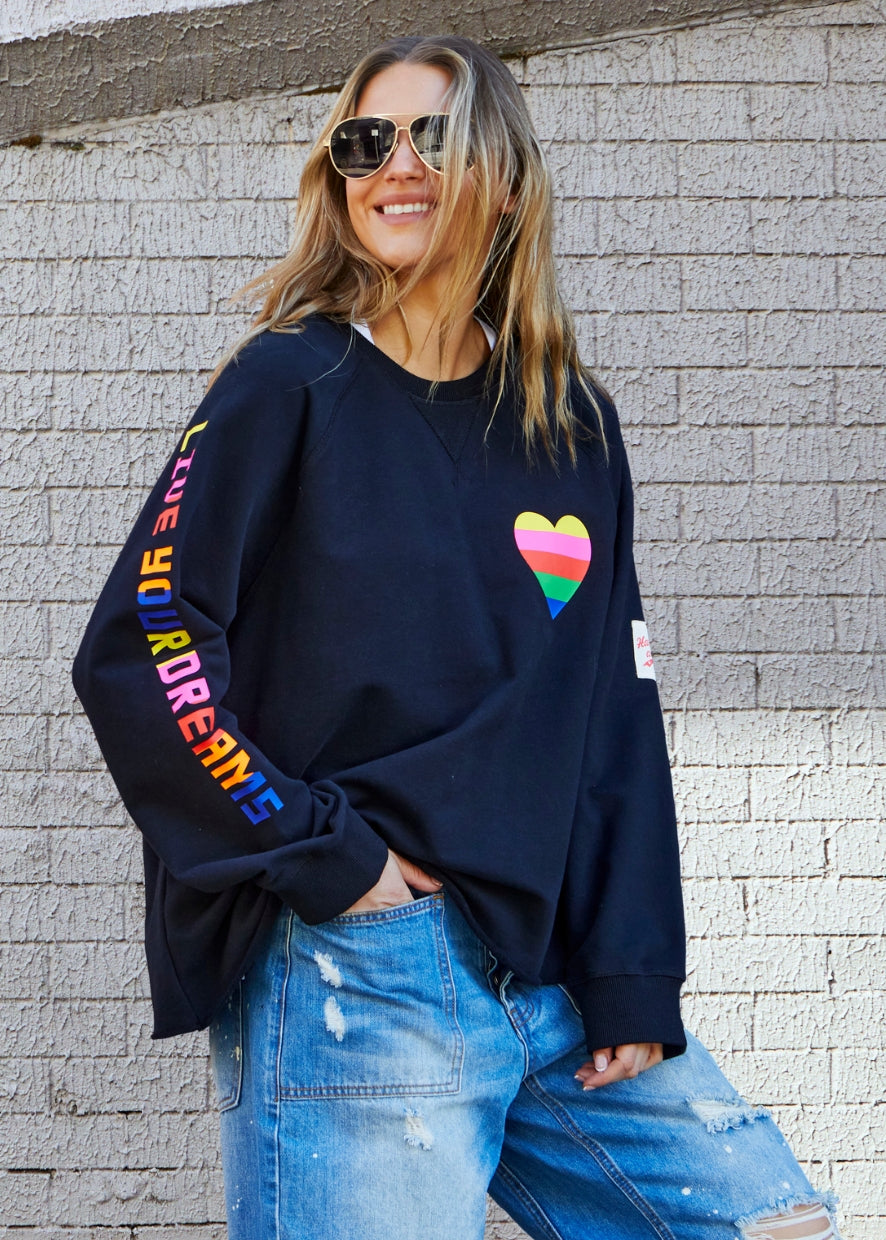 Hammill & Co Black sweat with small multi coloured heart print on the left chest and multi coloured FOLLOW YOUR DREAMS down the right sleeve