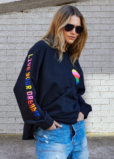 Hammill & Co Black sweat with small multi coloured heart print on the left chest and multi coloured FOLLOW YOUR DREAMS down the right sleeve