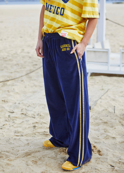 Hammill & Co New wider leg track pant in our luxurious, lightweight velour with velour stripes down each leg, draw cord and Hammill and Co logo print on left hem. The fit is a true to size, not oversized.